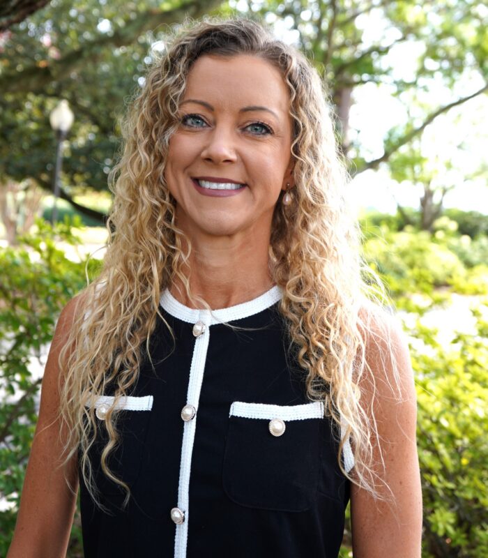 Meet Our Team - Professional and Welcoming Group at a Conference Table Faces the Camera, Team Leader Sitting on the Table with Arms Folded